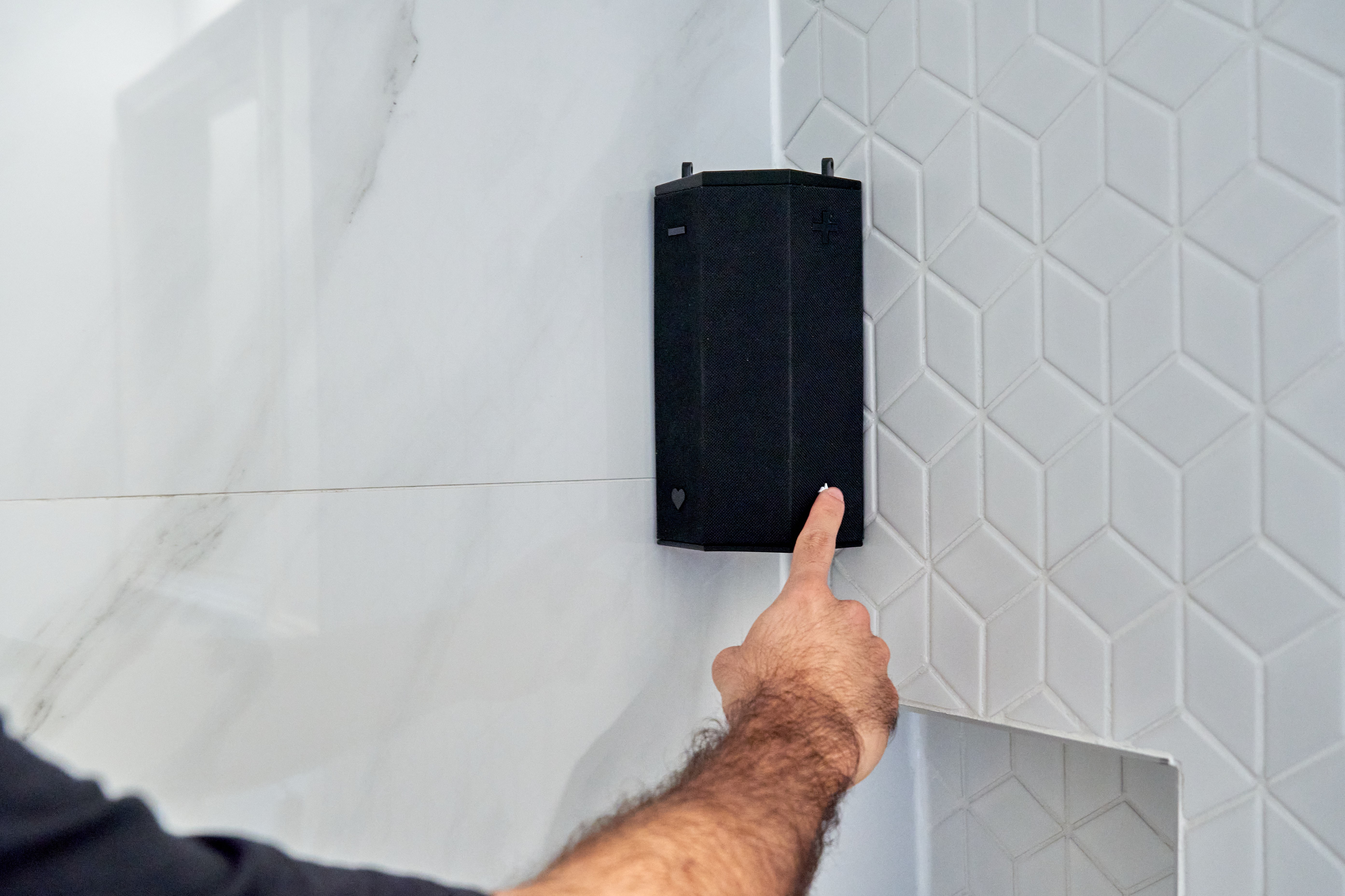 close-up image of a person's hand clicking a button on the speaker